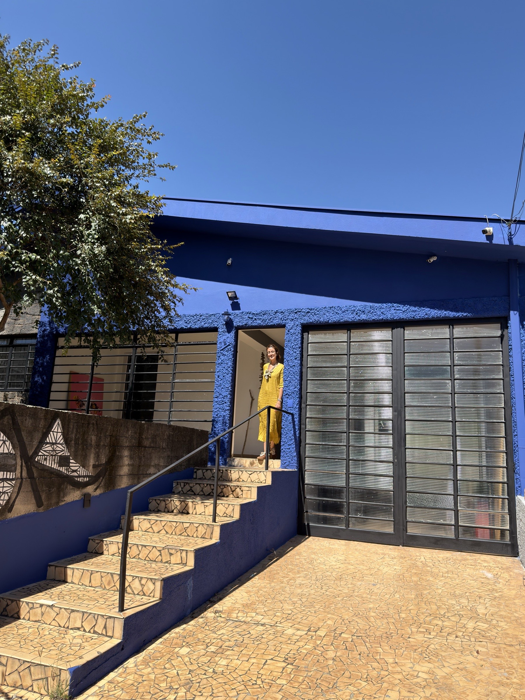 Fachada azul do Ateliê CASA, com Estefania Gavina na porta de entrada